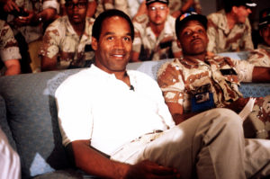 NBC Sports commentator and former professional football player O.J. Simpson sits with a group of servicemen to watch a Thanksgiving Day football game.  Simpson is visiting U.S. troops who are in the region for Operation Desert Shield.